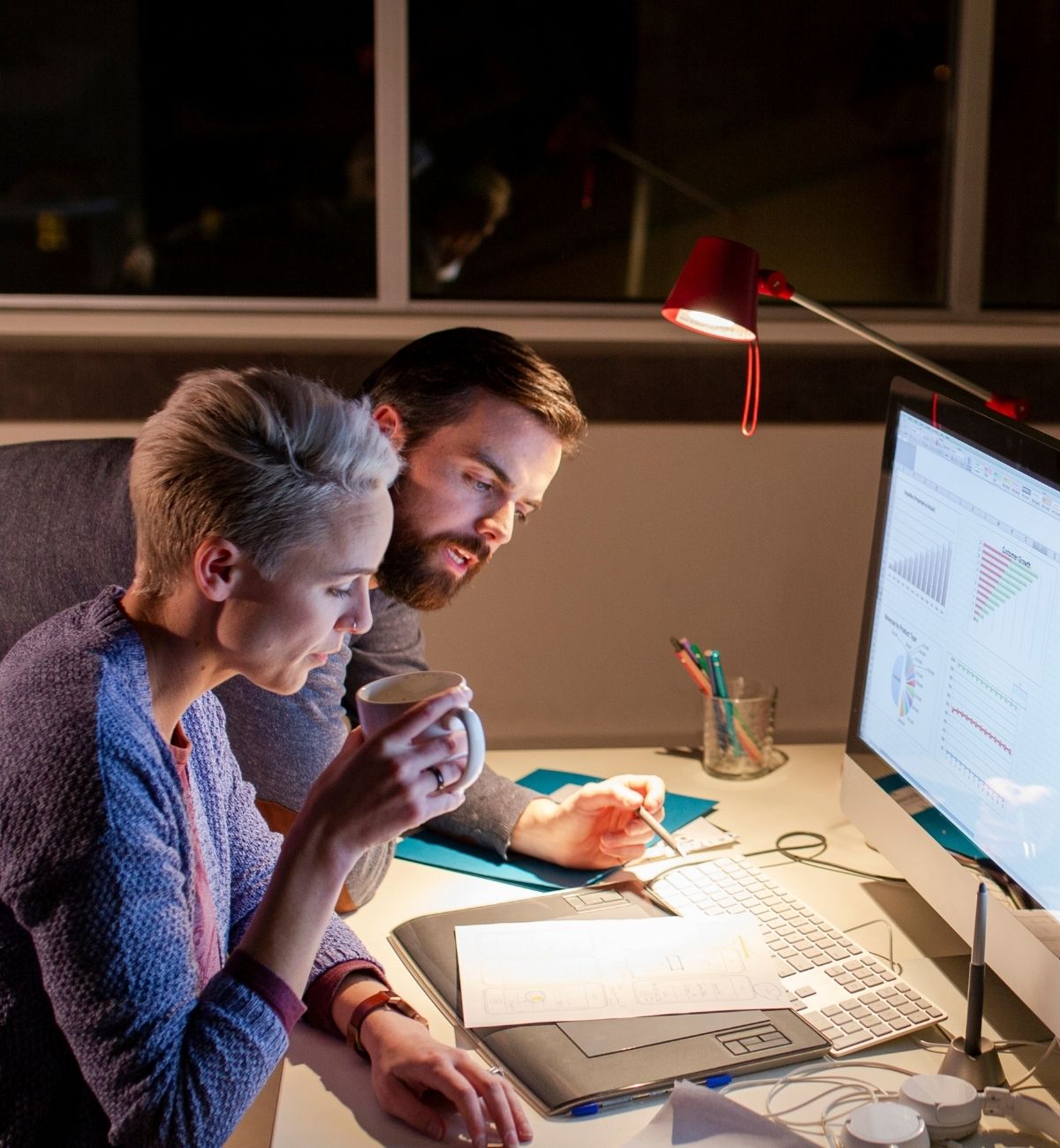 Business owners reviewing merchant cash advance debt and payment options at a desk late at night
