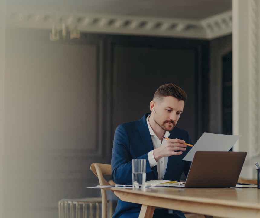 Small business owner at a desk reviewing multiple merchant cash advance payment statements