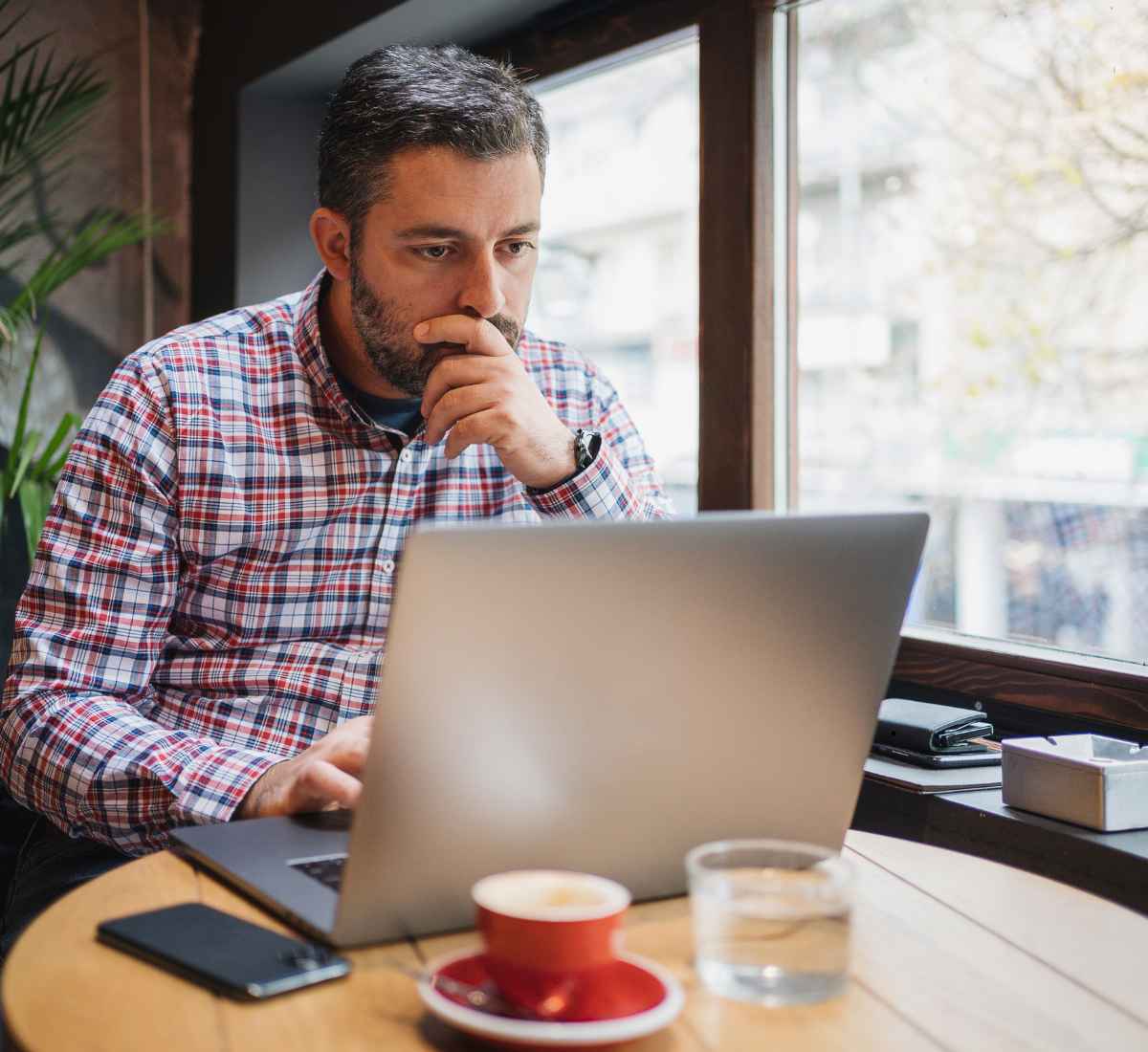Business owner reading Rise Alliance reviews and comparing MCA debt companies on a laptop