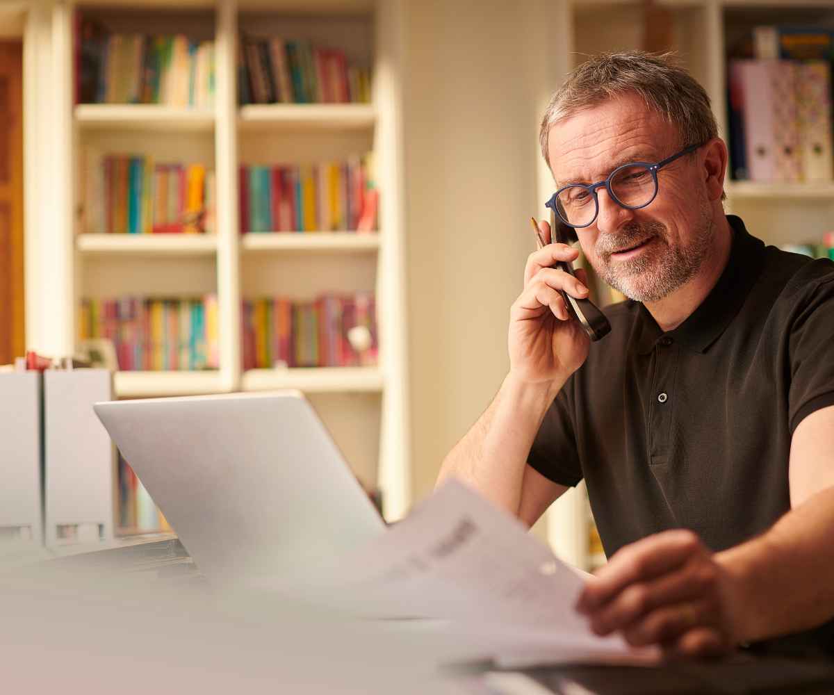 Small business owner on a phone call reviewing paperwork at his desk