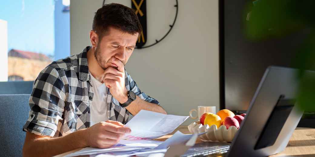 Business owner studying documents at a table while weighing a law firm or a program