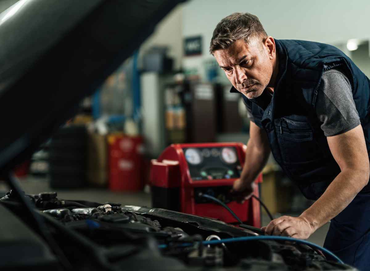 Auto repair shop owner working on a car engine, MCA debt relief for small businesses
