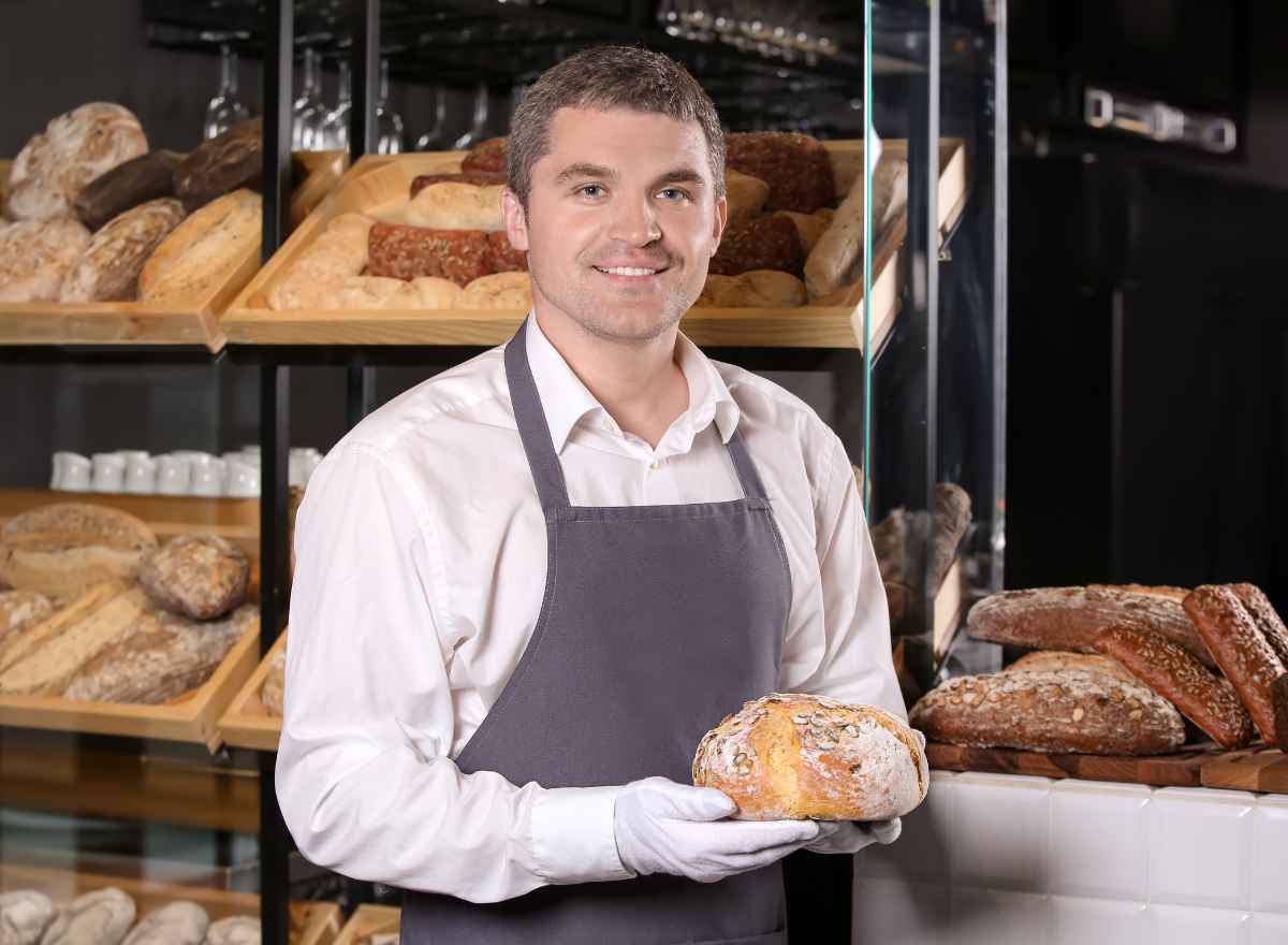 Bakery owner holding fresh bread, MCA debt relief keeps your business open
