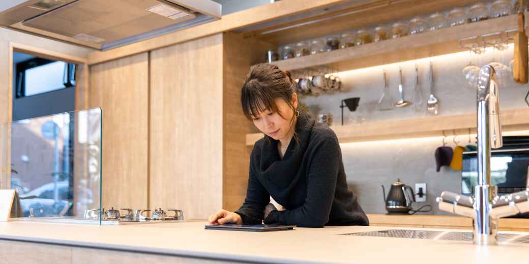 Restaurant owner leaning on the kitchen counter of her business working on a tablet