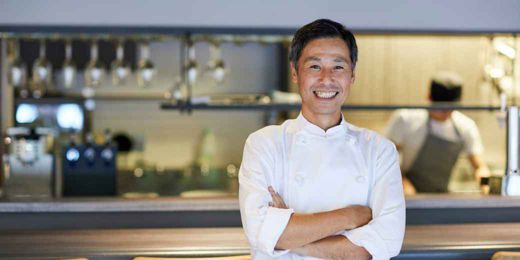 Restaurant owner smiling with arms crossed in his kitchen
