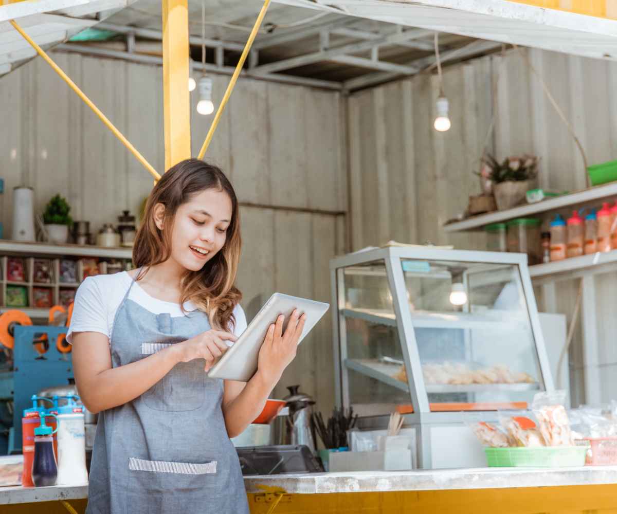 Small business owner at her shop counter checking a tablet