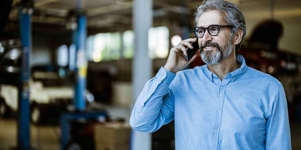 Auto repair shop owner on a phone call in the garage